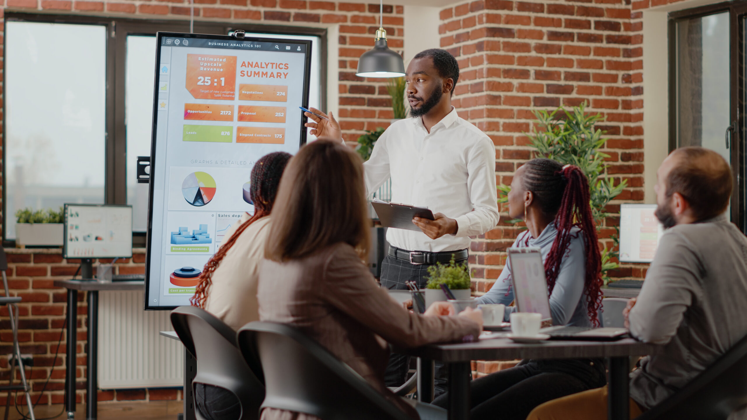 Company employee presenting business strategy with charts on monitor